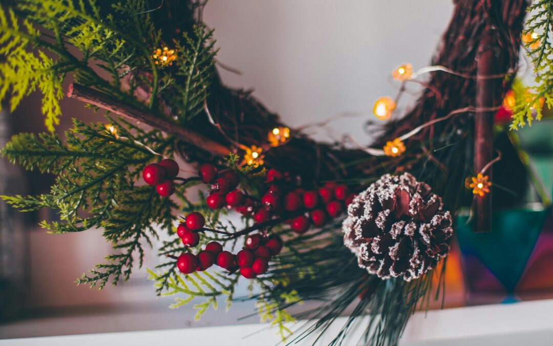 Wreath with berries and pine cone and lights hanging in home